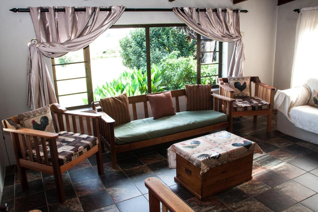 - un salon avec un canapé, des chaises et une fenêtre dans l'établissement Rusthof Accommodation, à Gansbaai