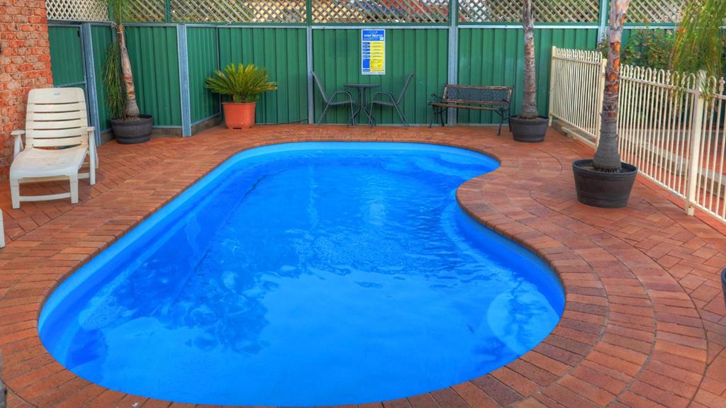 a swimming pool with blue water on a brick patio at Endeavour Court Motor Inn in Dubbo