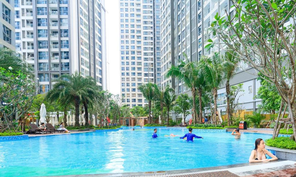 un grupo de personas en una piscina con edificios altos en Vinhomes Central Park -Luxury Christine Apartment, en Ho Chi Minh