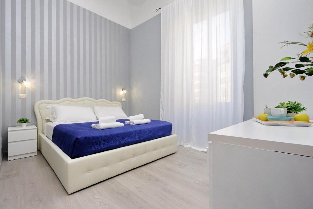 1 dormitorio blanco con 1 cama con manta azul en Domus Domas - Golden Keys Collection, en Roma