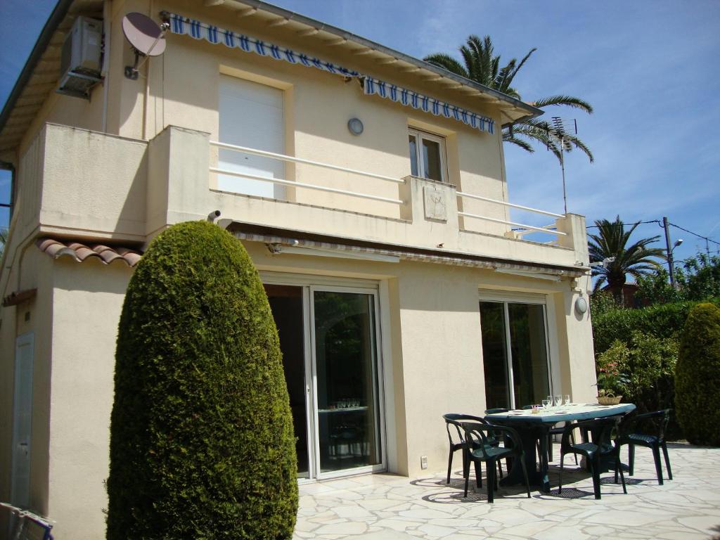 una casa con una mesa y sillas frente a ella en Villa L'Adret et sa piscine, en Juan-les-Pins