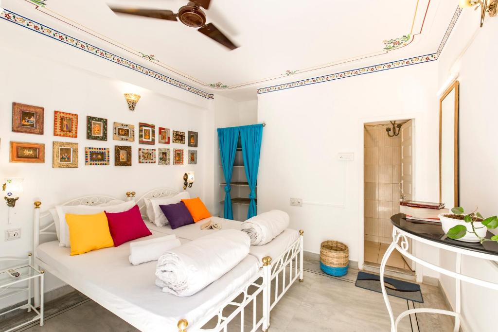 Habitación con cama blanca y almohadas coloridas. en goSTOPS Udaipur en Udaipur