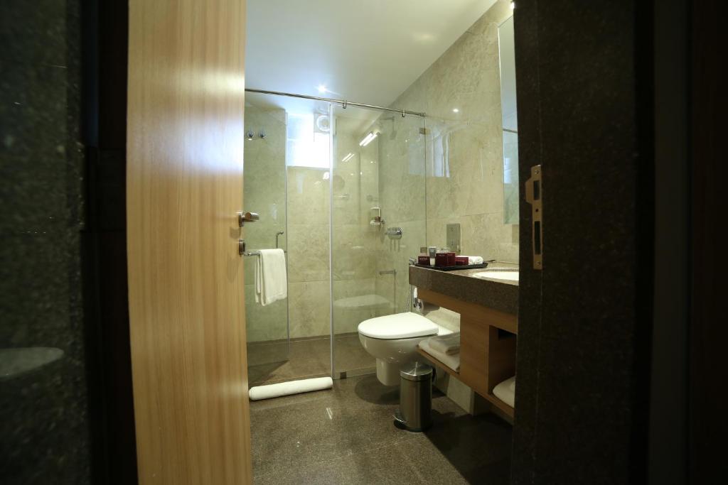 a bathroom with a toilet and a glass shower at Native INN By Heda Hospitality in Belgaum