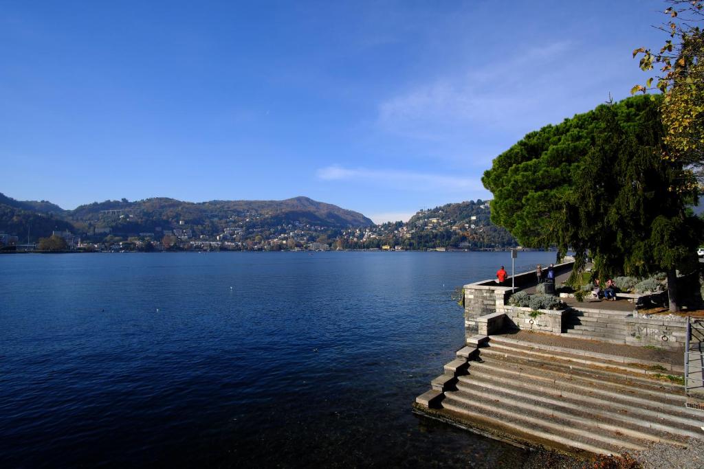 a person sitting on a bench near a body of water at Locanda Milano in Brunate