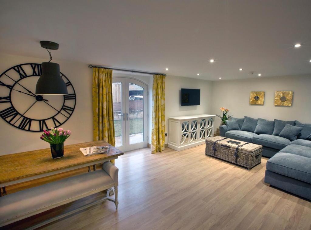 a living room with a large clock and a couch at Honeysuckle Cottage, Drift House Holiday Cottages in Astbury