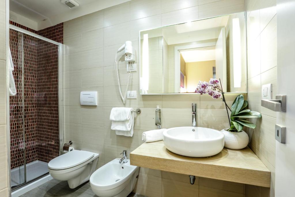 a bathroom with a sink and a toilet and a mirror at Alma di Alghero Hotel in Alghero