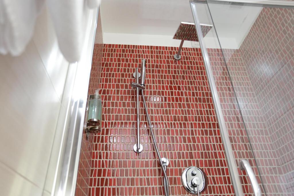a bathroom with a shower with red tile at Alma di Alghero Hotel in Alghero