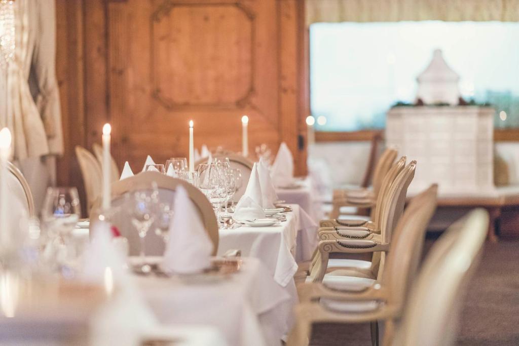 a dining room with white tables and chairs with candles at Schlosshotel Ischgl 5-Sterne Superior in Ischgl