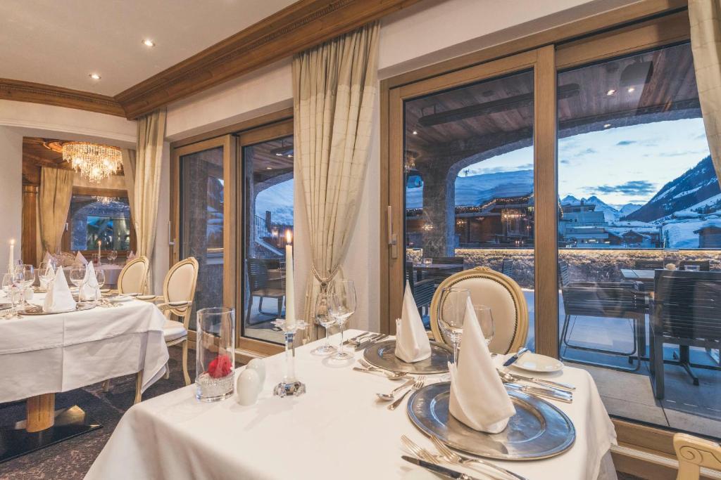a restaurant with white tables and chairs and windows at Schlosshotel Ischgl 5-Sterne Superior in Ischgl
