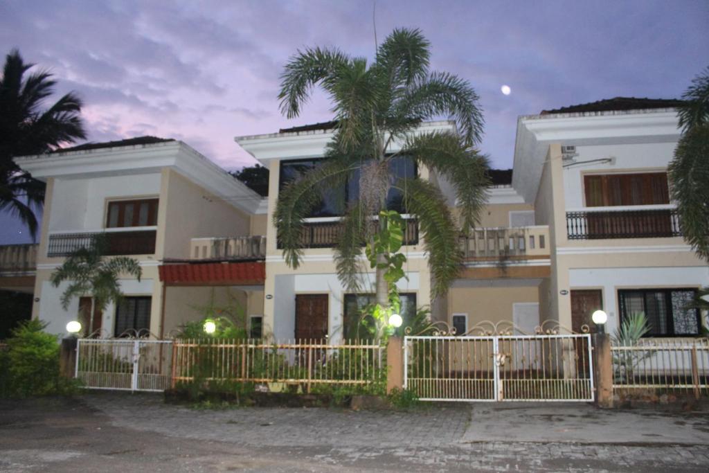 a house with a fence and a palm tree at Rosvilla Guest House in Benaulim