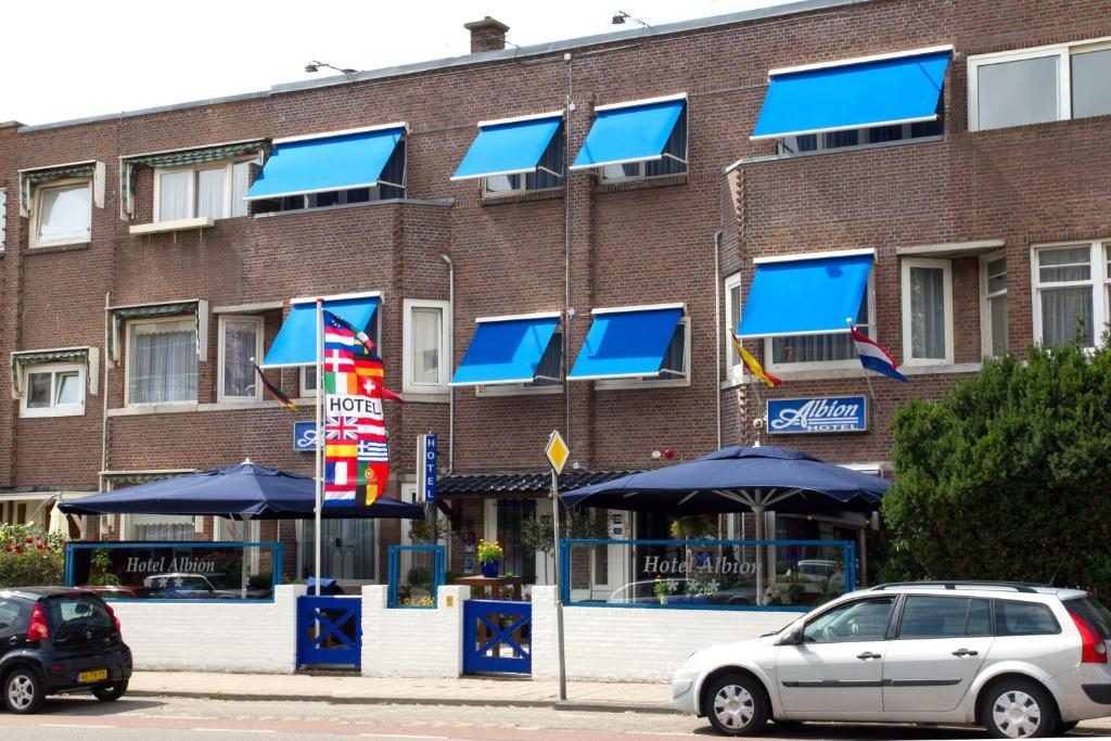 ein Backsteingebäude mit blauen Sonnenschirmen davor in der Unterkunft Hotel Albion in Scheveningen