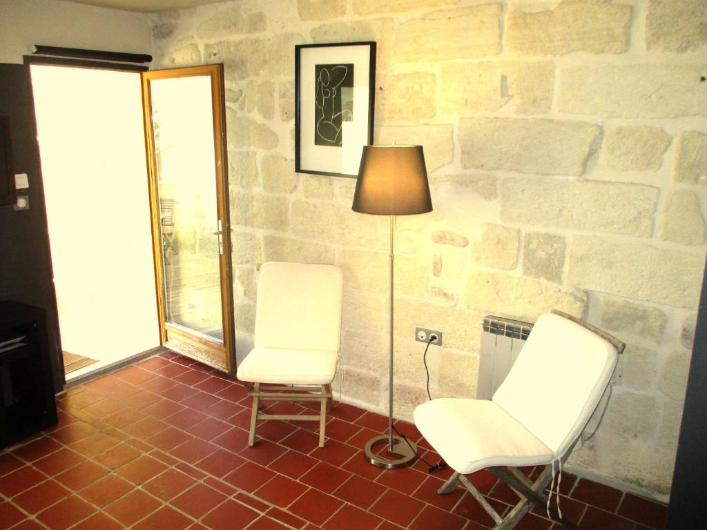two chairs and a lamp in a room with a stone wall at Les toîts d&#39;Uzès in Uzès