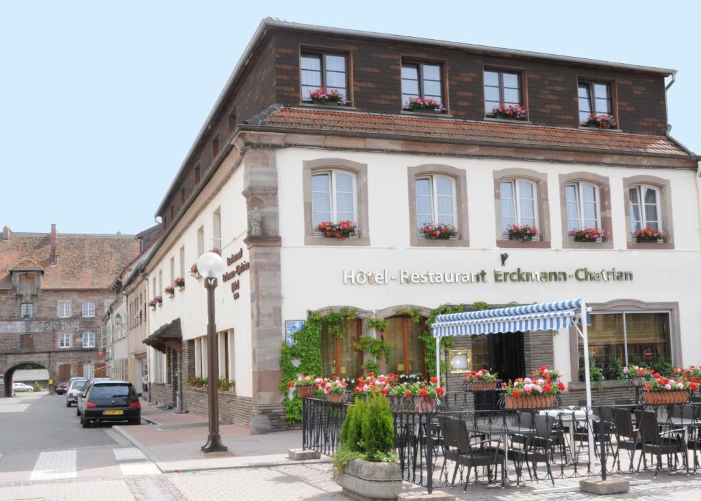 a building with tables and chairs in front of it at Hôtel Restaurant Erckmann Chatrian in Phalsbourg