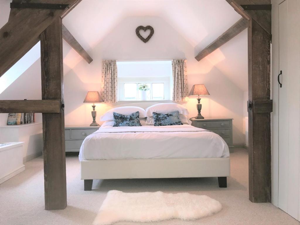 a bedroom with a white bed and a window at Cornerstone Cottage in Chipping Campden