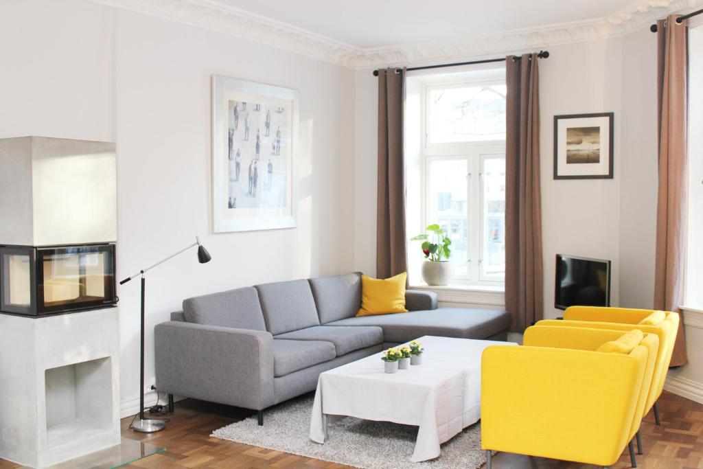 Nordic Host - Deichmans Gate 10 في أوسلو: غرفة معيشة مع أريكة رمادية وكراسي صفراء