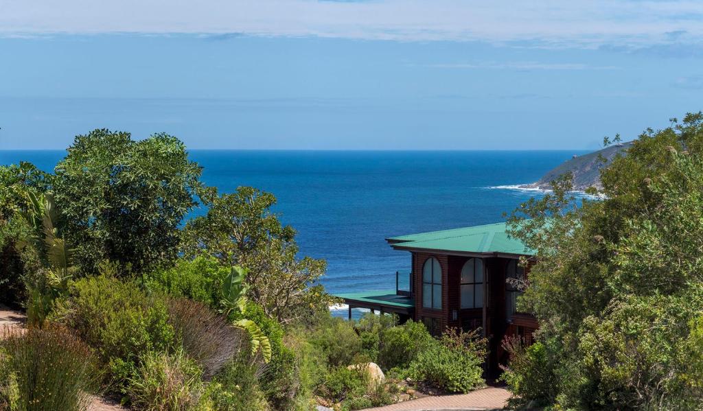 a house on a hill with the ocean in the background at Wilderness Gem Luxury Villa in Wilderness