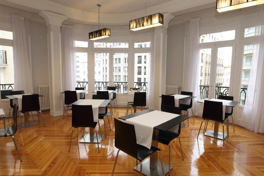 a dining room with tables and chairs and windows at Rincón de Gran Vía in Madrid