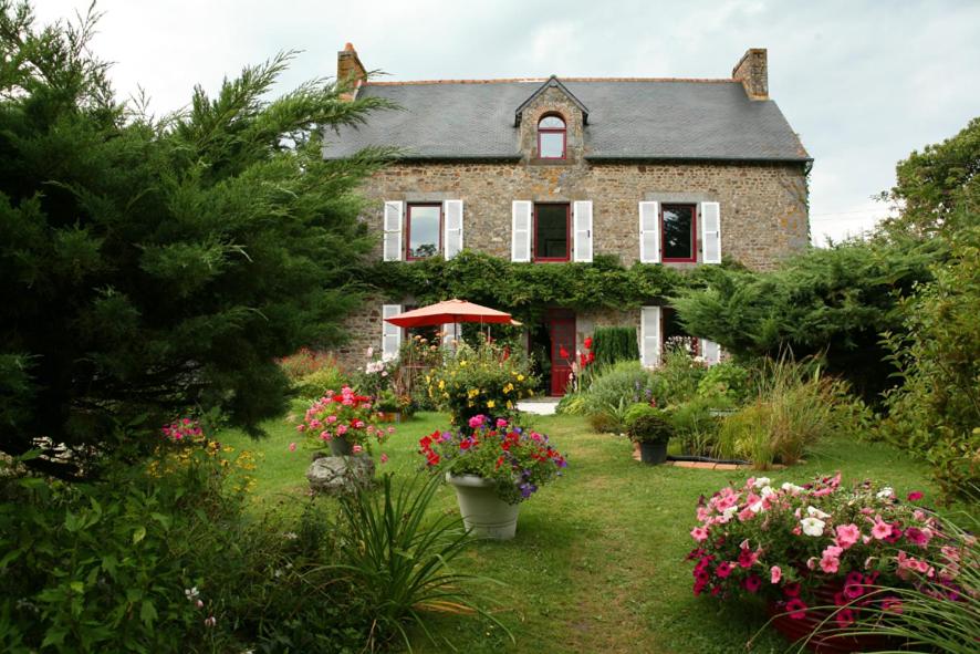 una gran casa de ladrillo con flores en el patio en Chambres d'Hôtes de la Barrerie, en Dingé