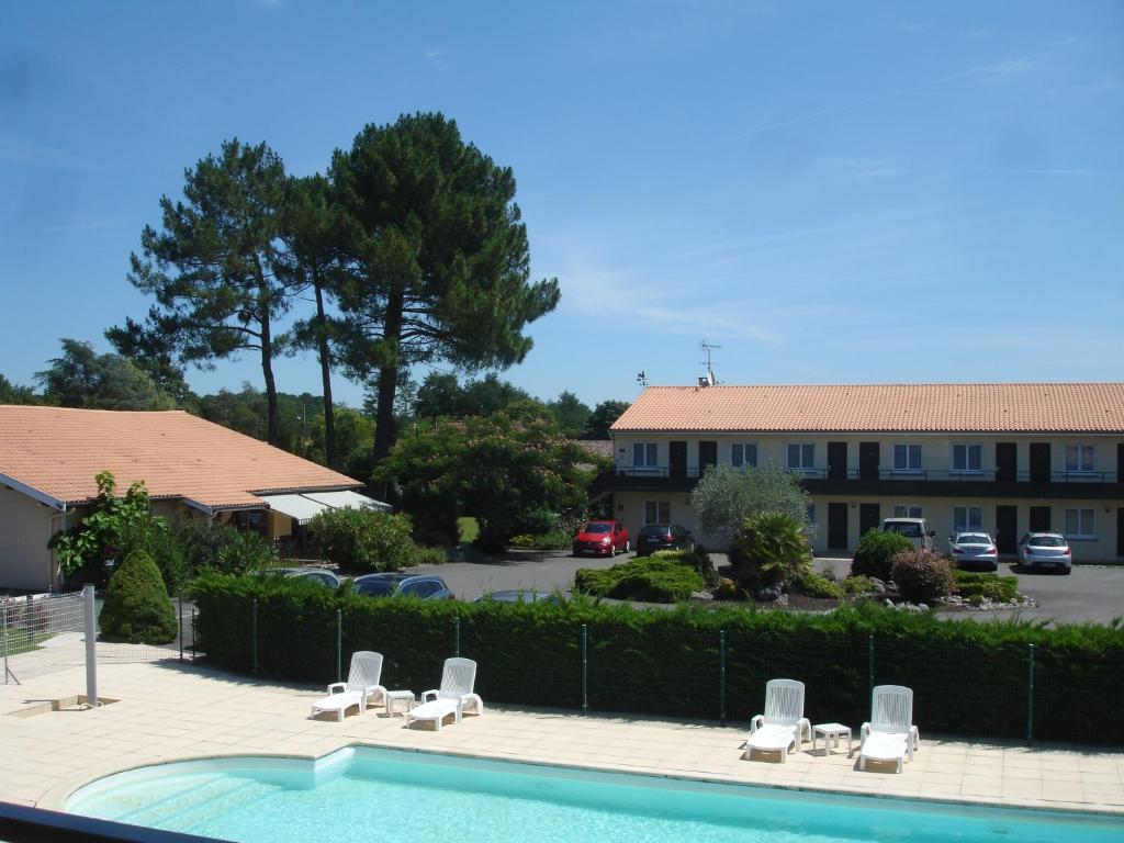 einen Pool mit Liegestühlen und ein Gebäude in der Unterkunft Hôtel Restaurant Les Bruyères in Saint-Médard-en-Jalles