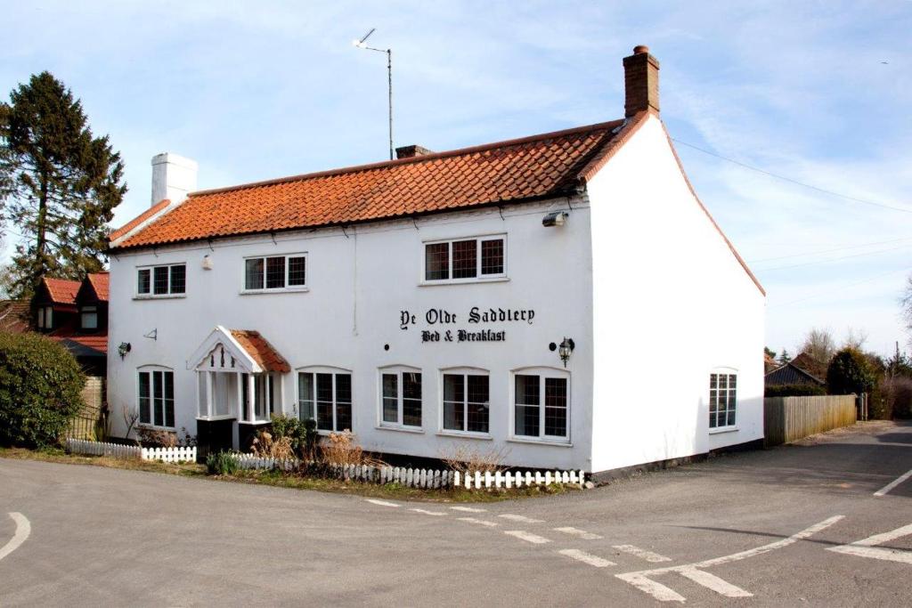 a white building with a sign on the side of it at Ye Olde Saddlery B&B in Neatishead