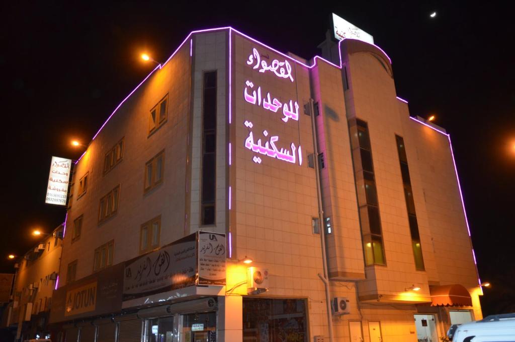 a building with neon signs on the side of it at Al Qaswaa Furnished Apartements in Buraydah