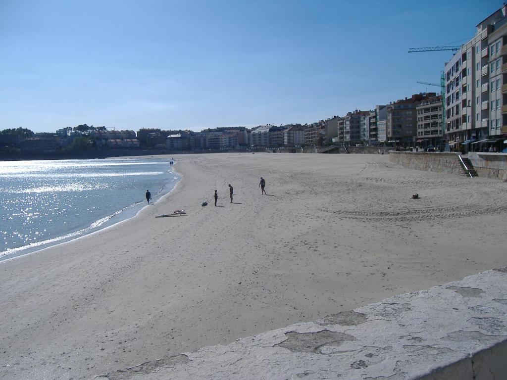 a group of people on a beach near the water at Alojamiento Ines in Sanxenxo