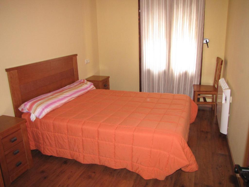 una camera da letto con un letto con una coperta arancione e una finestra di Benages-Chiva a Puertomingalvo