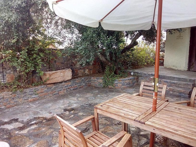 une table et des chaises en bois avec un parasol dans l'établissement Traditional House in Elounda, à Elounda