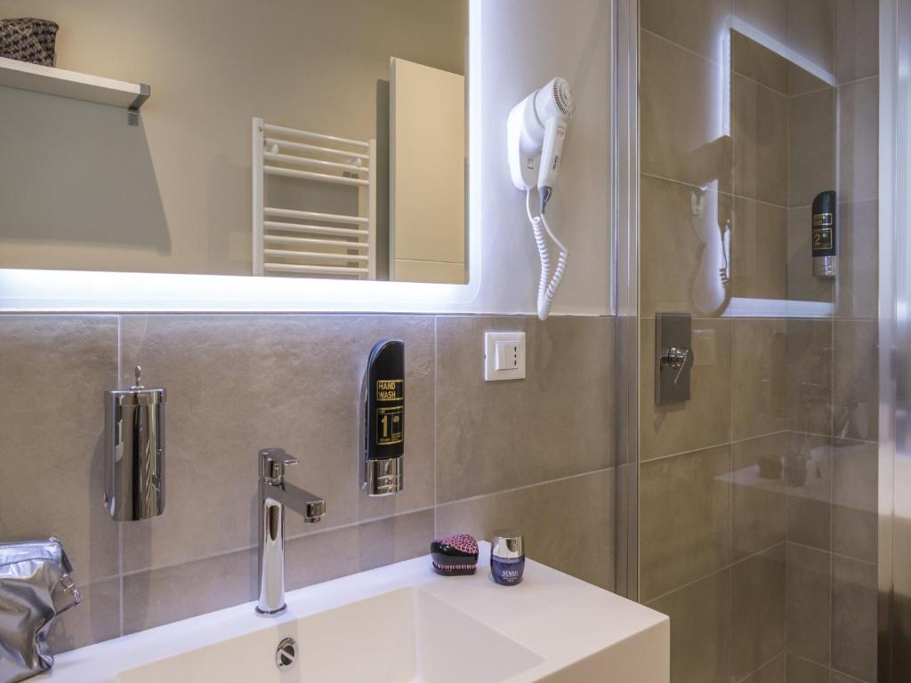 a bathroom with a sink and a shower with a phone at Hotel Buena Onda in Peschiera del Garda