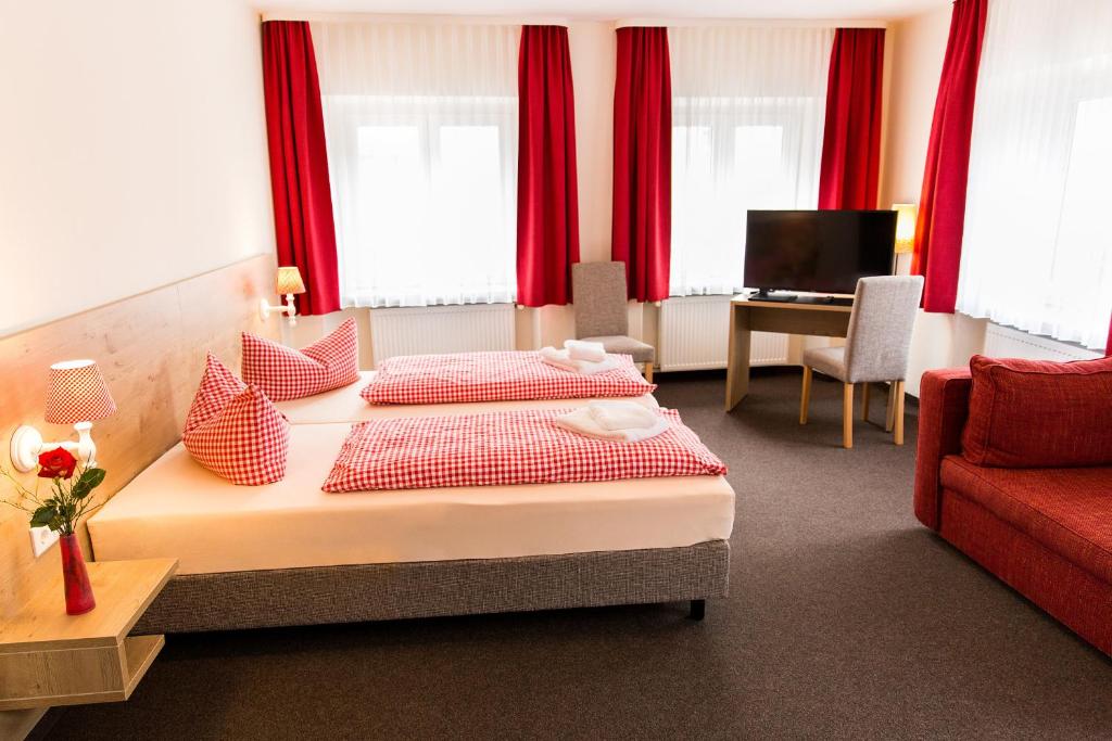 Habitación de hotel con 2 camas y sofá rojo en Braugasthof Trompete, en Eichstätt