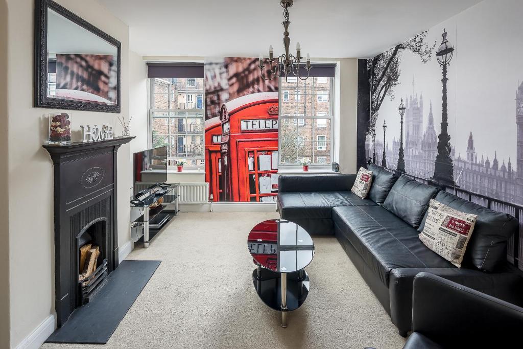 a living room with a black couch and a red phone booth at Skyline Serviced Apartments - London Bridge in London