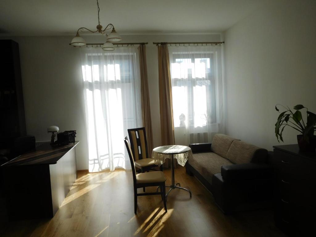 a living room with a couch and a table and two windows at Apartament DERUBEIS in Wieliczka