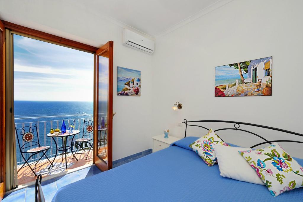 a bedroom with a bed and a balcony with the ocean at Chez Amélie in Amalfi