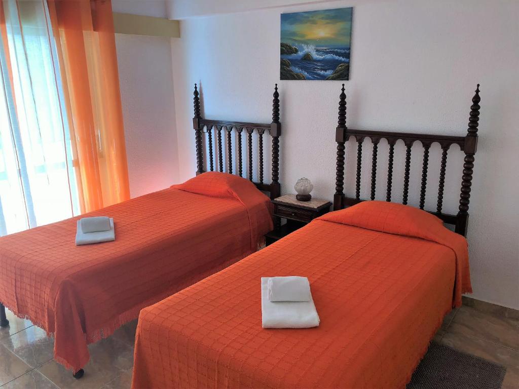 ラゴスにあるOlinda’s Roomsのオレンジのシーツが備わるベッド2台(1室あたり)