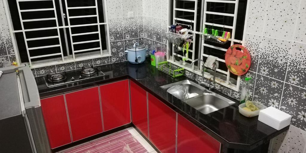 uma pequena cozinha com armários vermelhos e um lavatório em Hazim Homestay Changlun Pakej Esklusif em Changlun