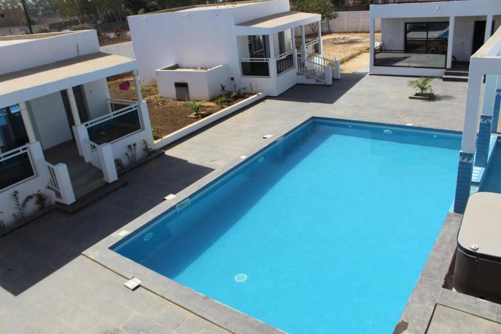 a large blue swimming pool in front of a house at Le Ngapatel Bungalow Thaï in Ngaparou