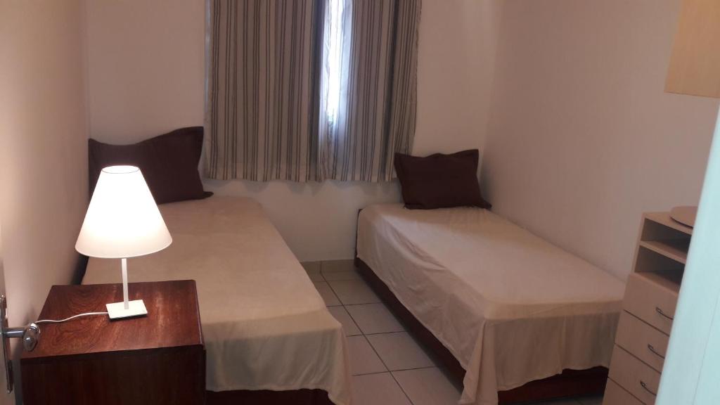 Cette petite chambre comprend deux lits et une lampe. dans l'établissement Relax.guarapari, à Guarapari