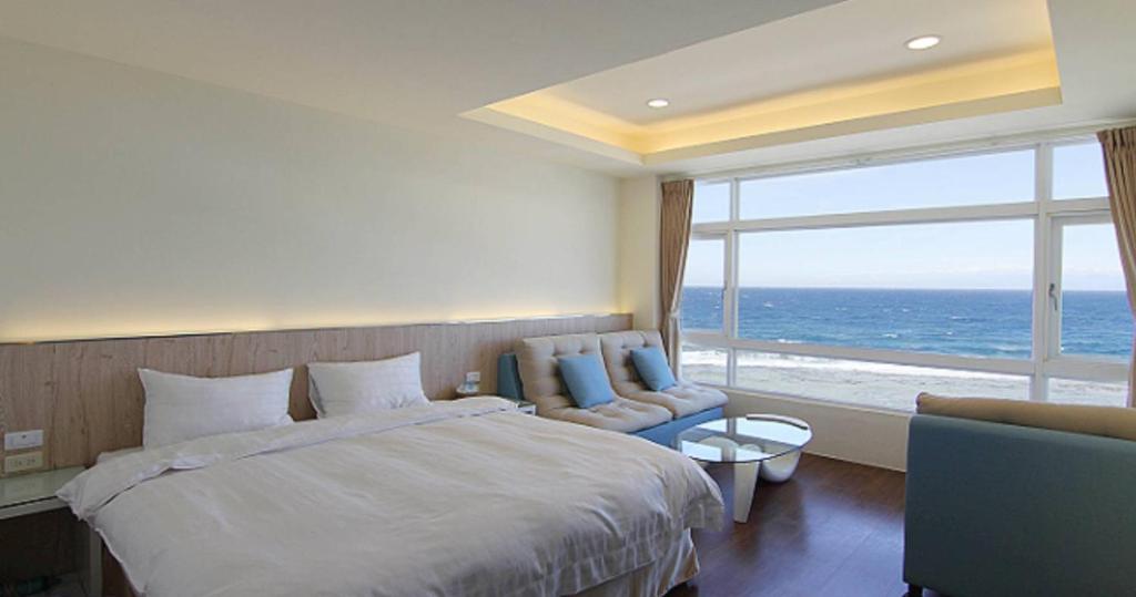 a bedroom with a large bed and a large window at 綠島 綠堤濱海旅店 in Green Island