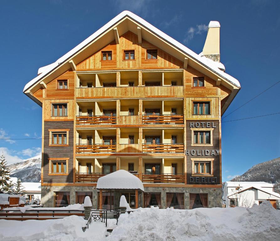 a large building with snow in front of it at Hotel Holiday Debili in Sauze dʼOulx