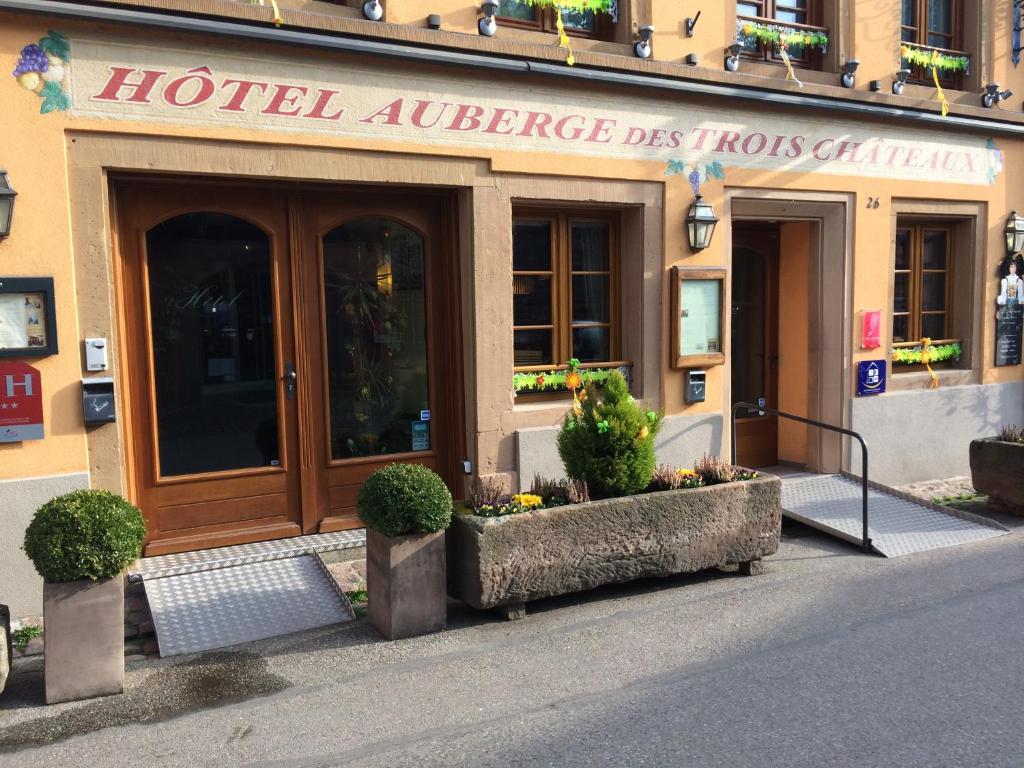 een hotelingang met planten voor een gebouw bij Auberge des Trois Châteaux in Eguisheim