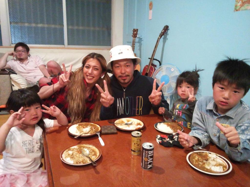 a group of people sitting at a table eating food at Little Asia Guest House in Naha