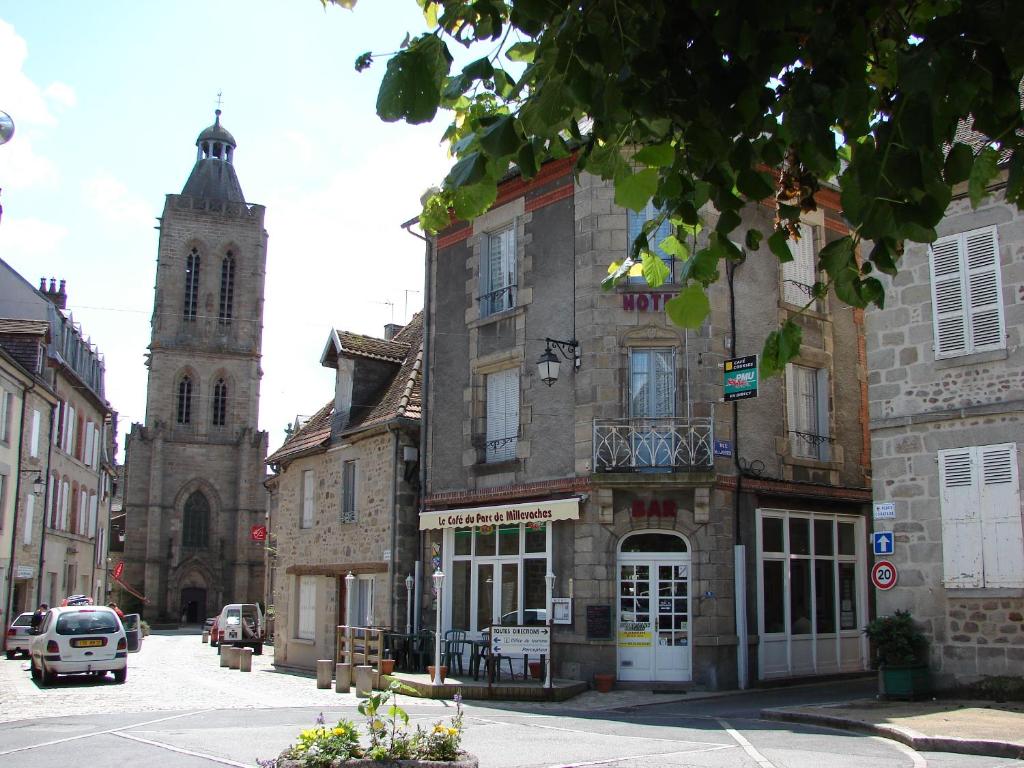 un antiguo edificio con una torre de reloj y una iglesia en Au Relais du Parc de Millevaches, en Felletin