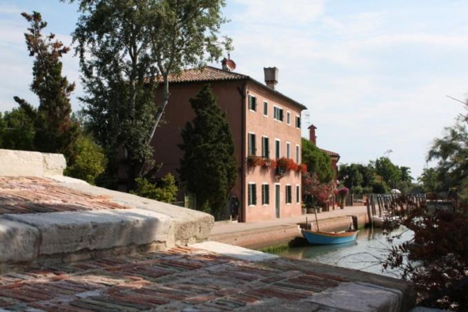 a building with a boat in the water next to a house at Ca' Torcello in Venice