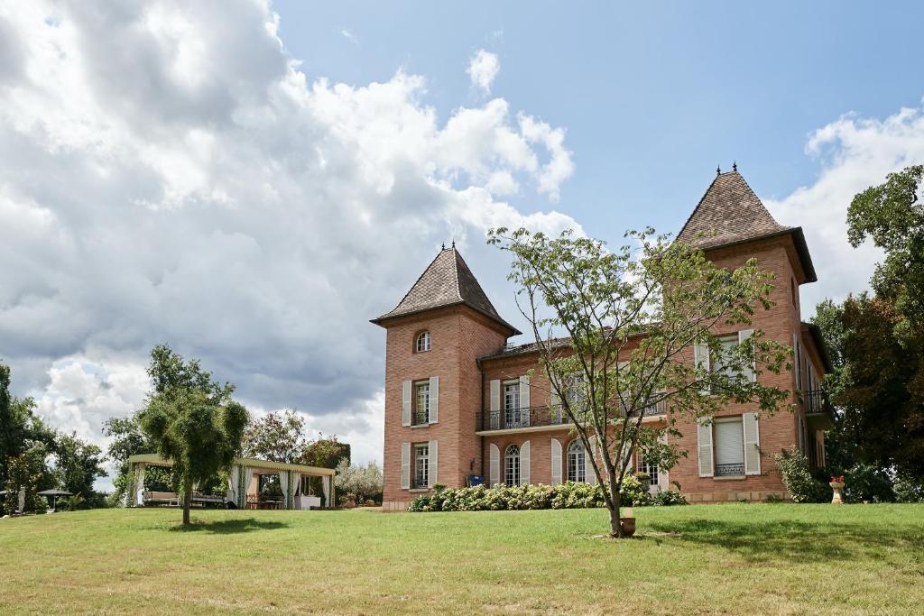 duży ceglany budynek z drzewem przed nim w obiekcie Castel Bois Marie w mieście Montauban