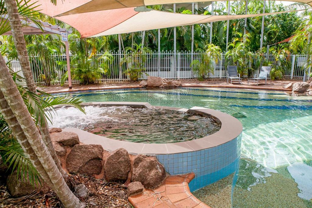 une grande piscine avec un parasol et une piscine dans l'établissement Nightcliff Foreshore Getaway - McKay Gardens, à Nightcliff