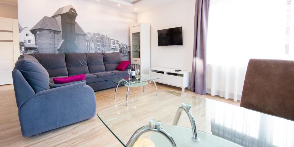 a living room with a blue couch and a tv at Apartment Milena in Gdańsk