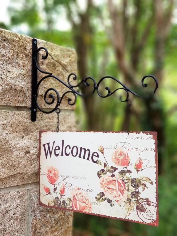 a sign hanging on a stone wall with a welcome sign at Around The Tree Manor in Shitan