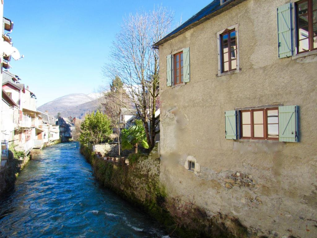 ein Fluss zwischen zwei Gebäuden neben einem Gebäude in der Unterkunft Les Deux Rives in Cierp