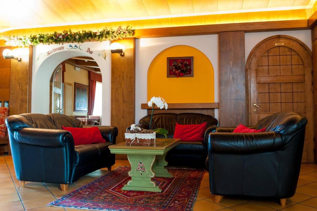 Residence Des Alpes في أسياجو: غرفة معيشة مع كراسي جلدية وطاولة