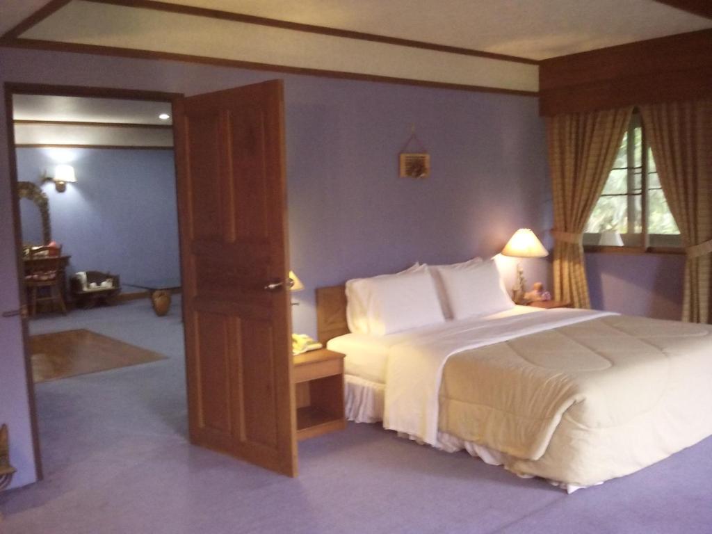 a bedroom with a large white bed and a window at Mae Rim Lagoon Bed & Bakery in Mae Rim